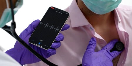 Arzt bei Verwendung des Littmann Digital-Stethoskops auf dem Brustkorb eines Patienten
